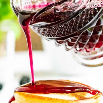 blackberry syrup being poured on pancakes.