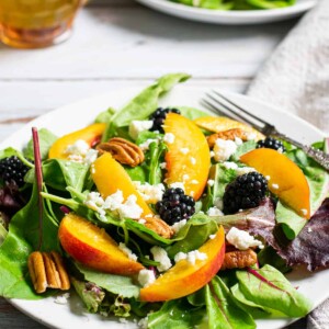 salad with peaches and blackberries on plate.