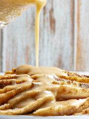 Sliced slow cooker turkey with gravy being poured out of a white pitcher.