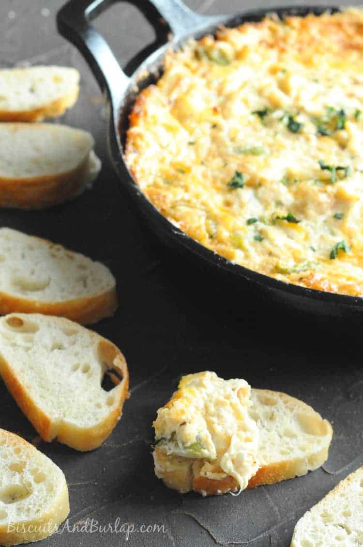 Cajun crab dip in a cast iron skillet surrounded by sliced French bread