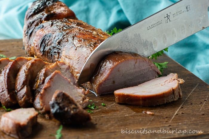 pork tenderloin being sliced on cutting board