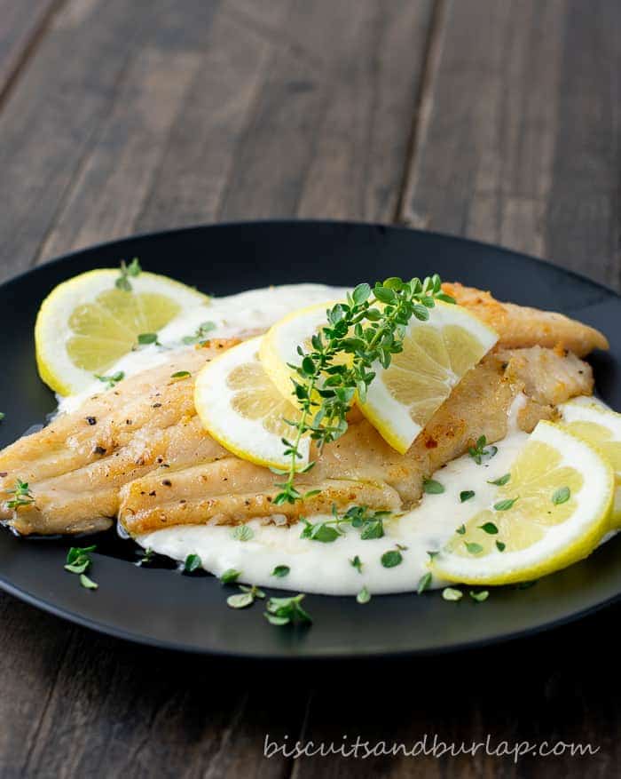 catfish on black plate with lemons and sauce