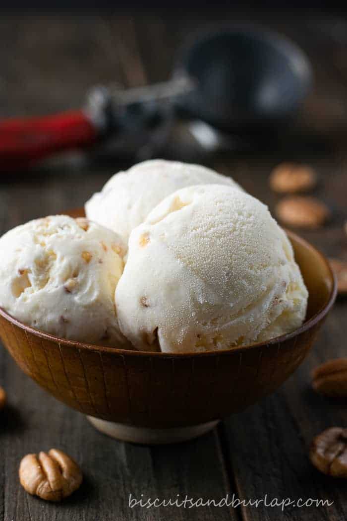 ice cream in brown pottery bowl with pecans and scoop