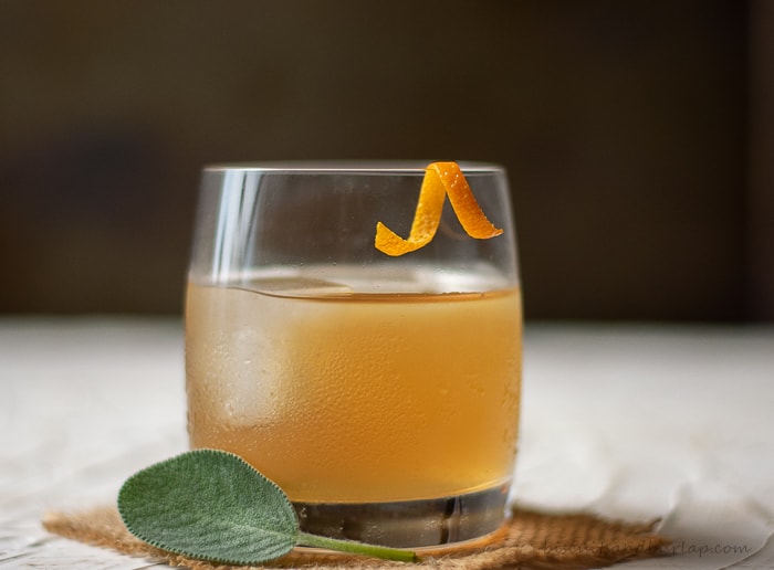 single bourbon cocktail with orange twist & sage leaf