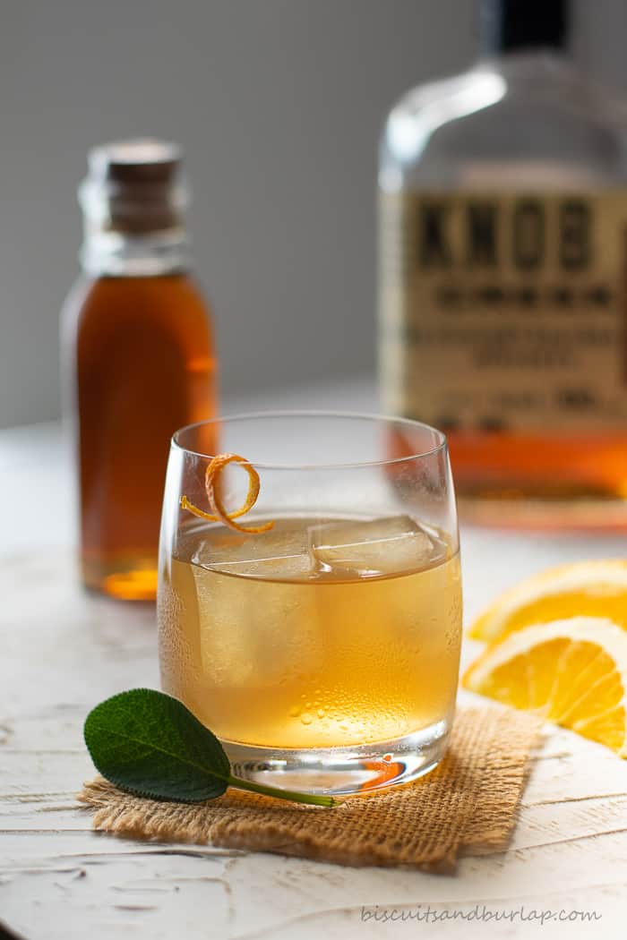 cocktail with honey, bourbon & orange behind it