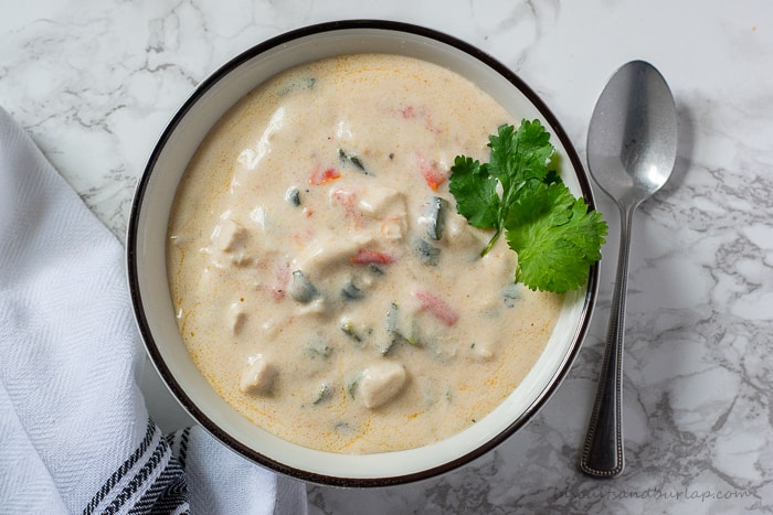 cheesy poblano pepper soup in bowl with spoon on marble