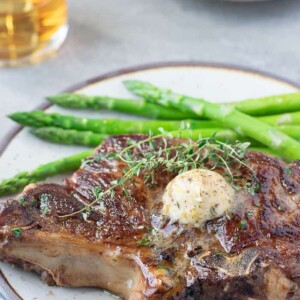 steak on plate with butter on top and asparagus on side