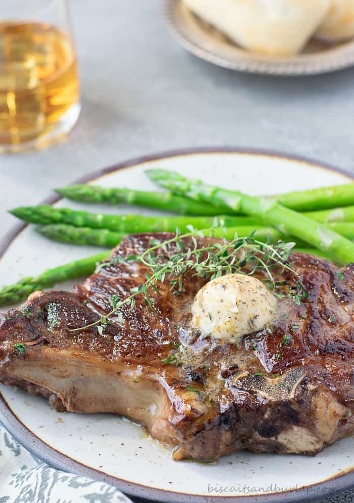 steak on plate with butter on top and asparagus on side