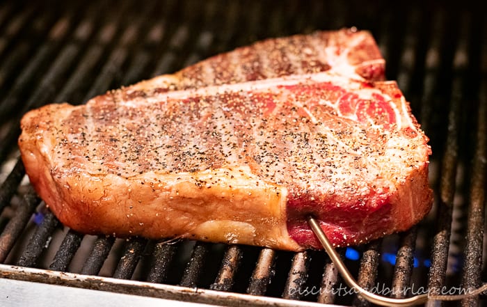 uncooked steak on grill with thermometer probe