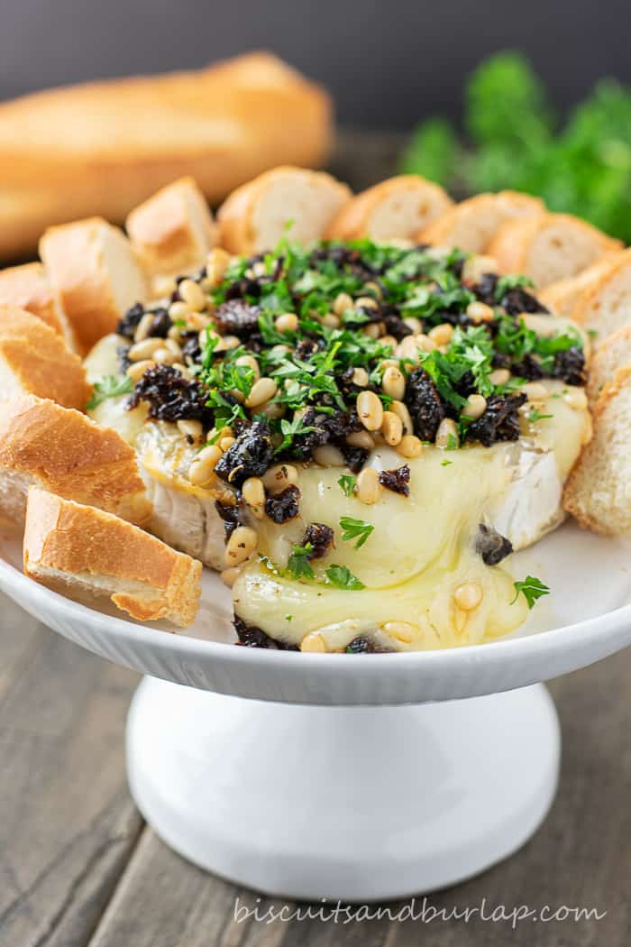 baked brie on stand surrounded by crostini