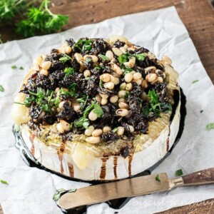 horizontal shot of baked brie cheese on parchment with knife
