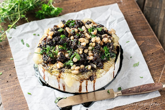 horizontal shot of baked brie on parchment with knife