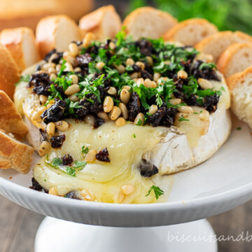 baked brie cheese on white plate with crostini
