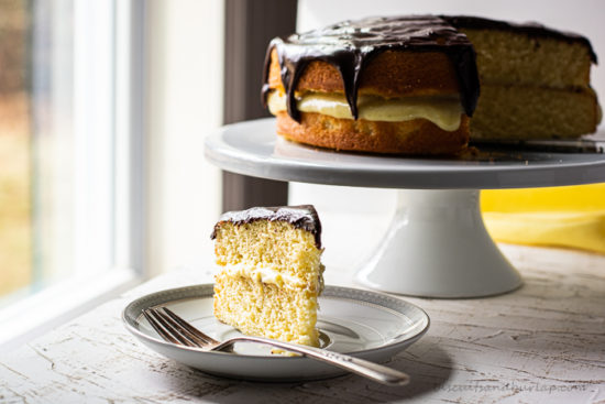 slice of boston cream pie on plate with whole cake behind