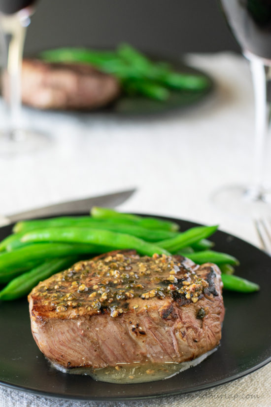 filet mignon sauce over steak with wine & second plate in background