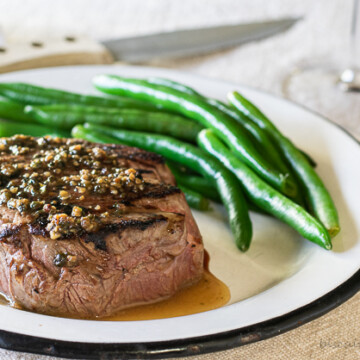 filet mignon sauce over steak with green beans and fork