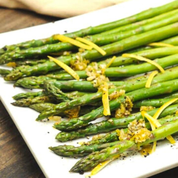roasted asparagus on square white plate.