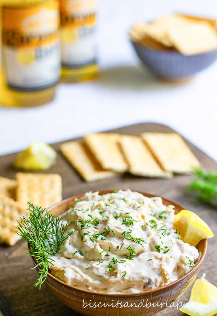 vertical shot of bowl of fish dip with crackers behind