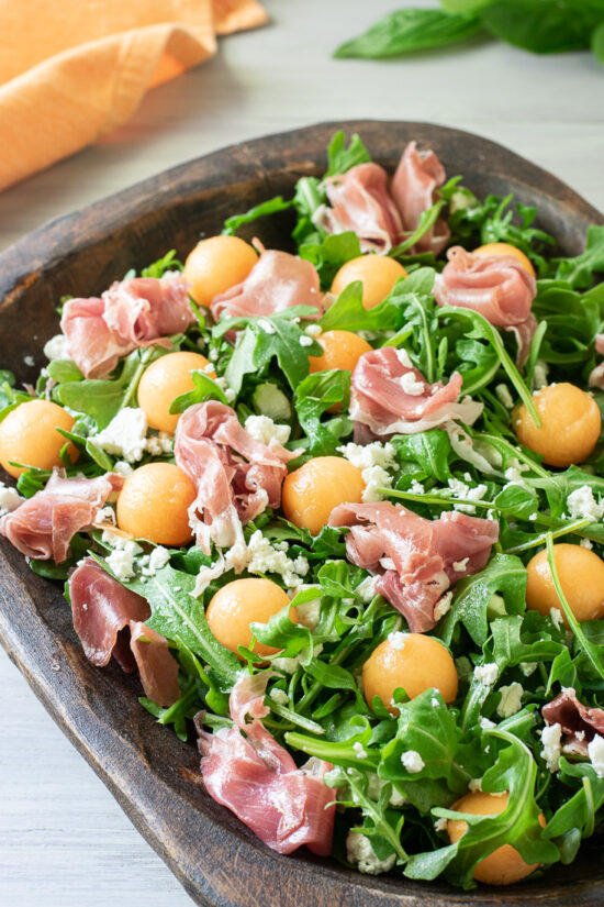 melon and prosciutto salad in wood bowl