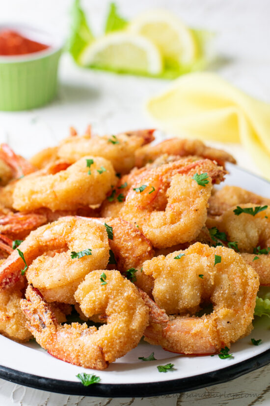 fried shrimp with lemons & cocktail sauce behind