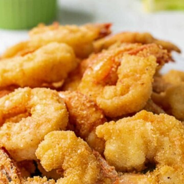fried shrimp with cocktail sauce and lemons behind.