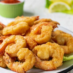 fried shrimp with cocktail sauce and lemons behind.