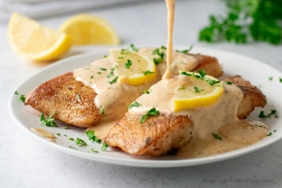 cajun cream sauce being poured over fish