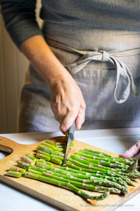woman in apron cutting asparagus