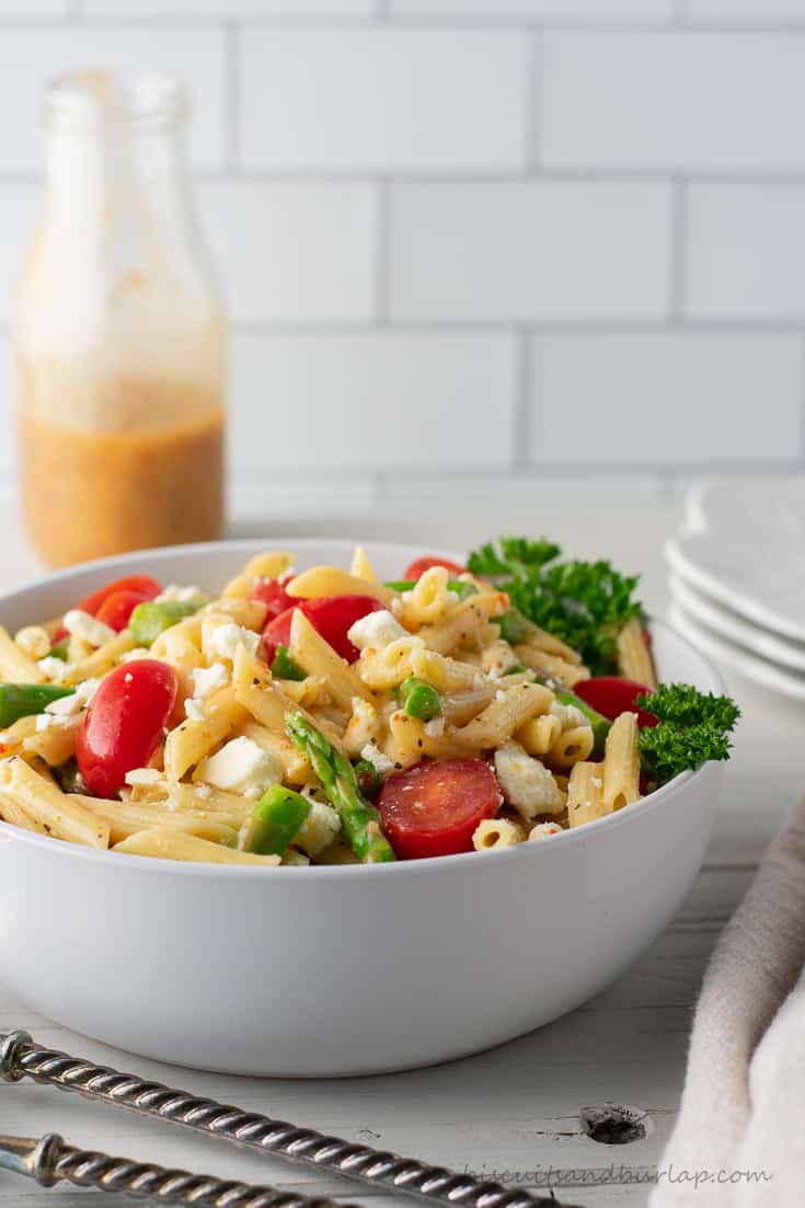 bowl of pasta salad with dressing behind