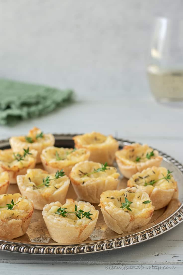 cheese tartlets on silver plate with glass of wine