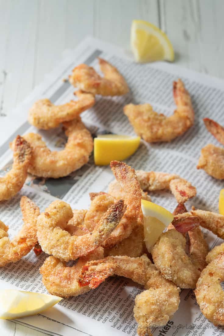 air fryer shrimp on newspaper with lemons