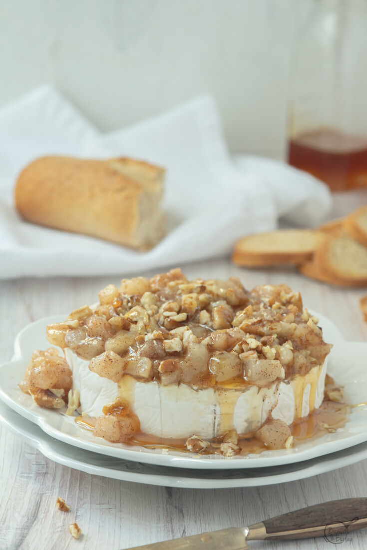 baked camembert on plate with bread and honey behind