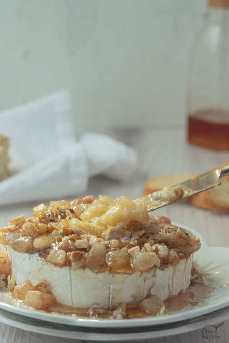 spreader scooping bite of baked camembert with honey