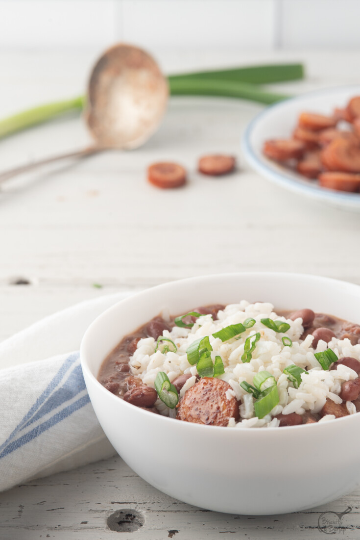 white bowl with cajun red beans and sauce and rice on top.