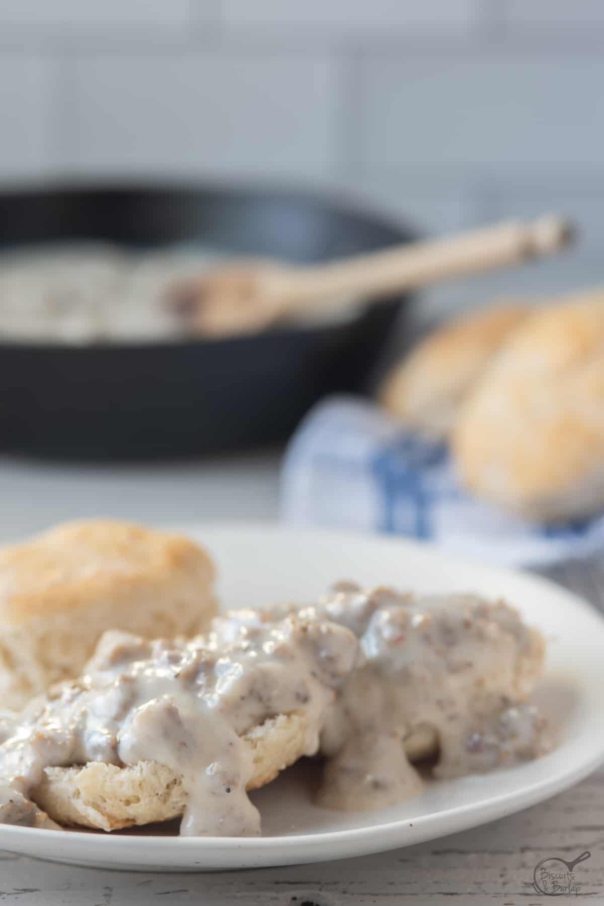 biscuits with sausage gravy over and skillet behind