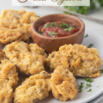 Fried oysters and cocktail sauce on white plate with title