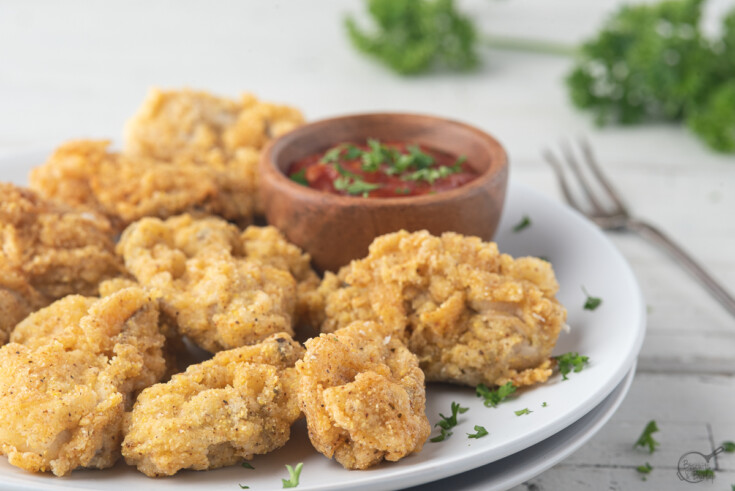 Fried oysters and cocktail sauce on white plate