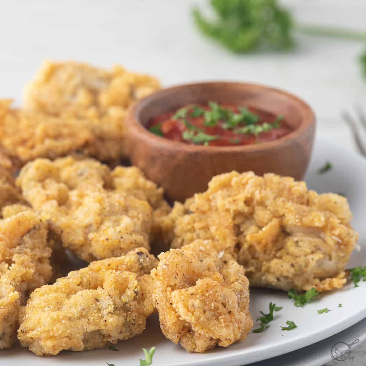 Fried oysters and cocktail sauce on white plate square image