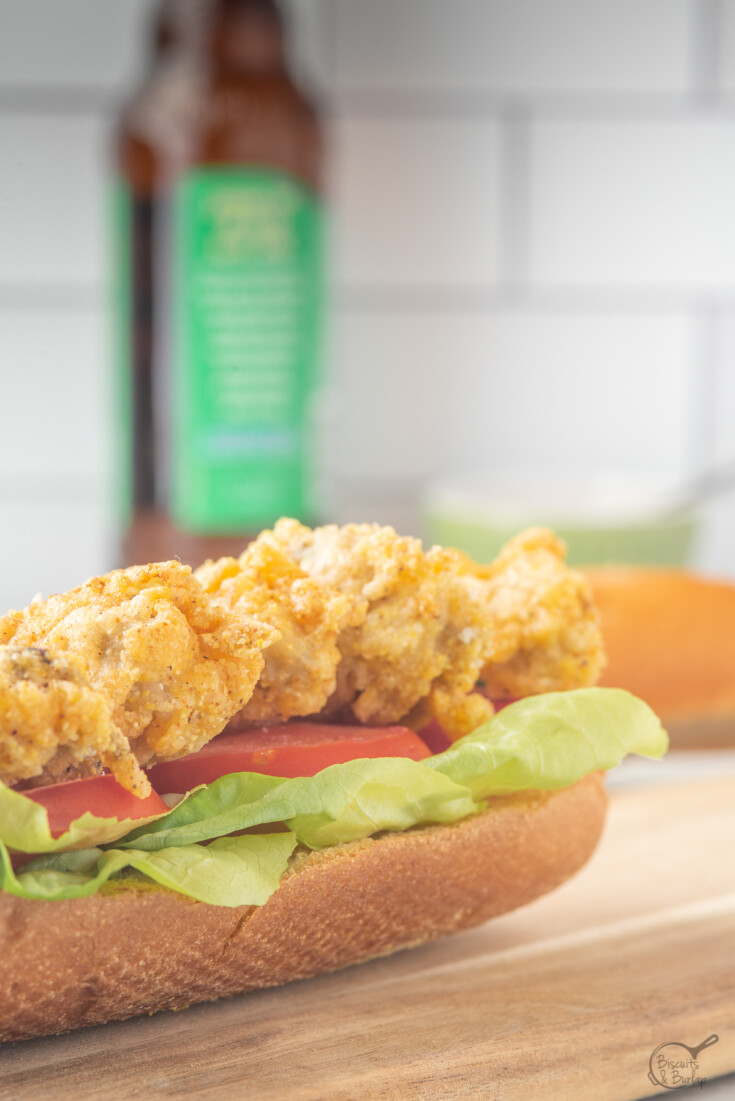 fried oyster po'boy on cutting board with beer in background