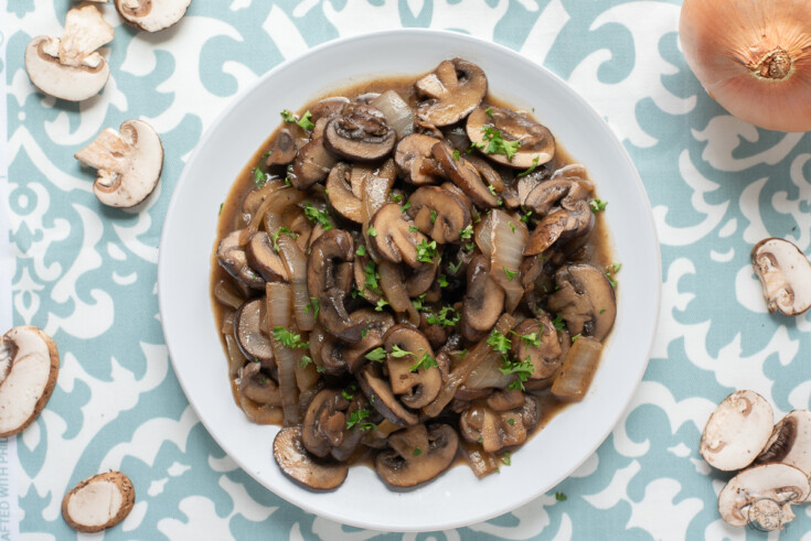 white plate with sauteed mushrooms and onions surrounded by raw veggies