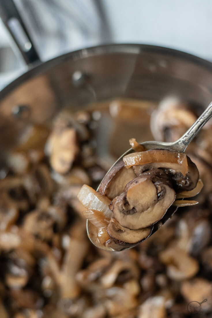 close up of mushrooms and onions for steak in spoon