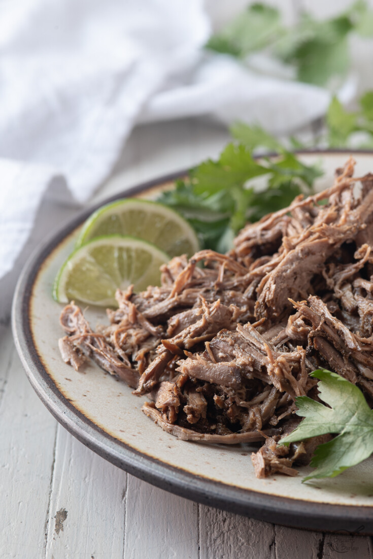 crock pot shreded beef on plate with limes