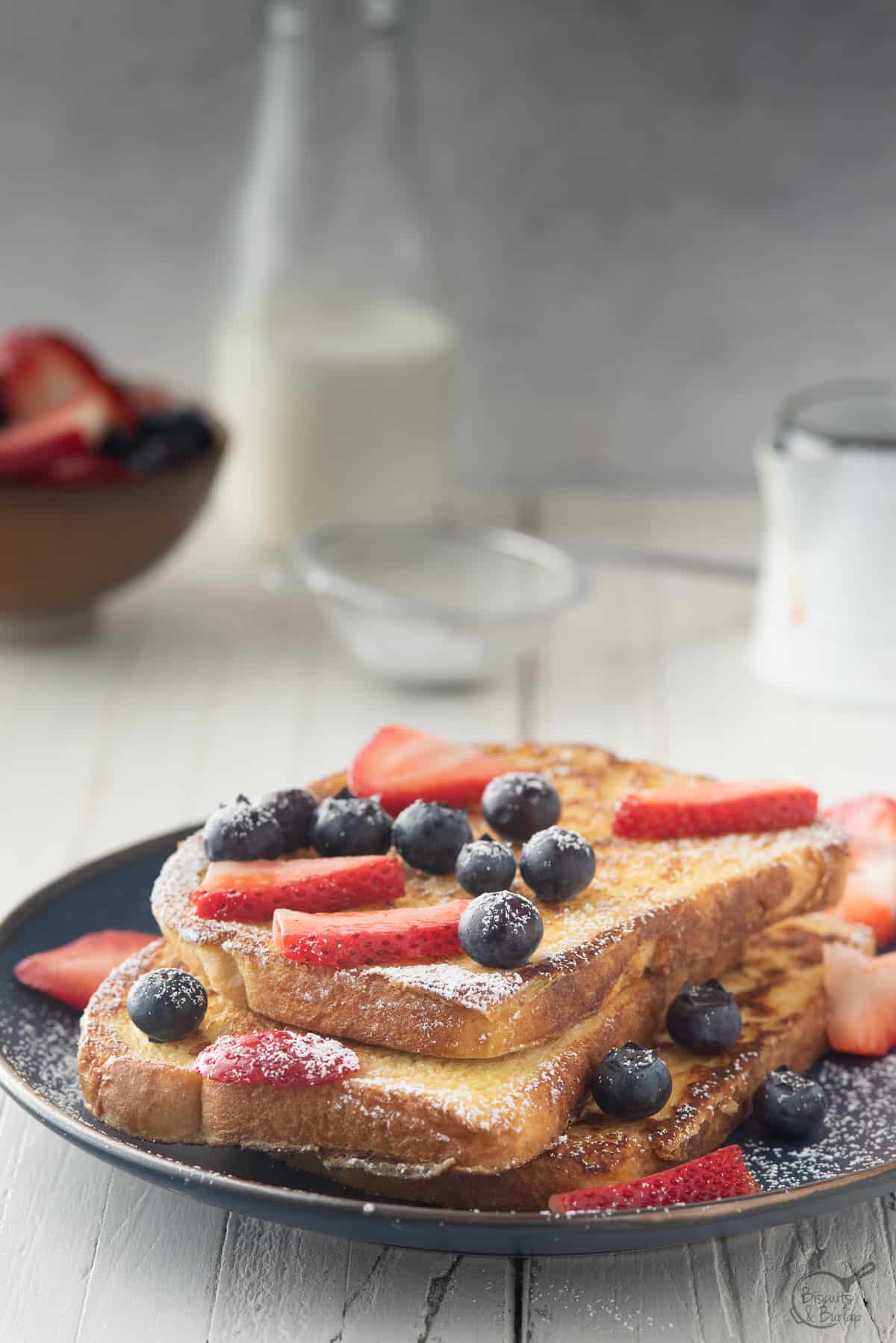 french toast made from sourdough with berries, milk & syrup behind.