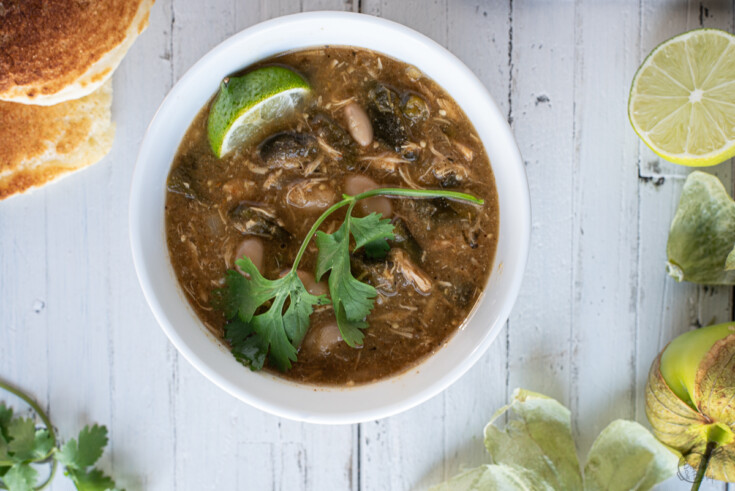 bowl of chicken chili with cornbread, lime and tomatillos.