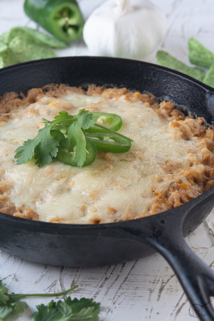 Corn dip with cream cheese in a cast iron skillet with tortilla chips and cilantro