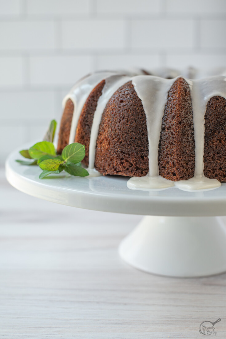 banana bread bundt cake with white glaze on cake stand.