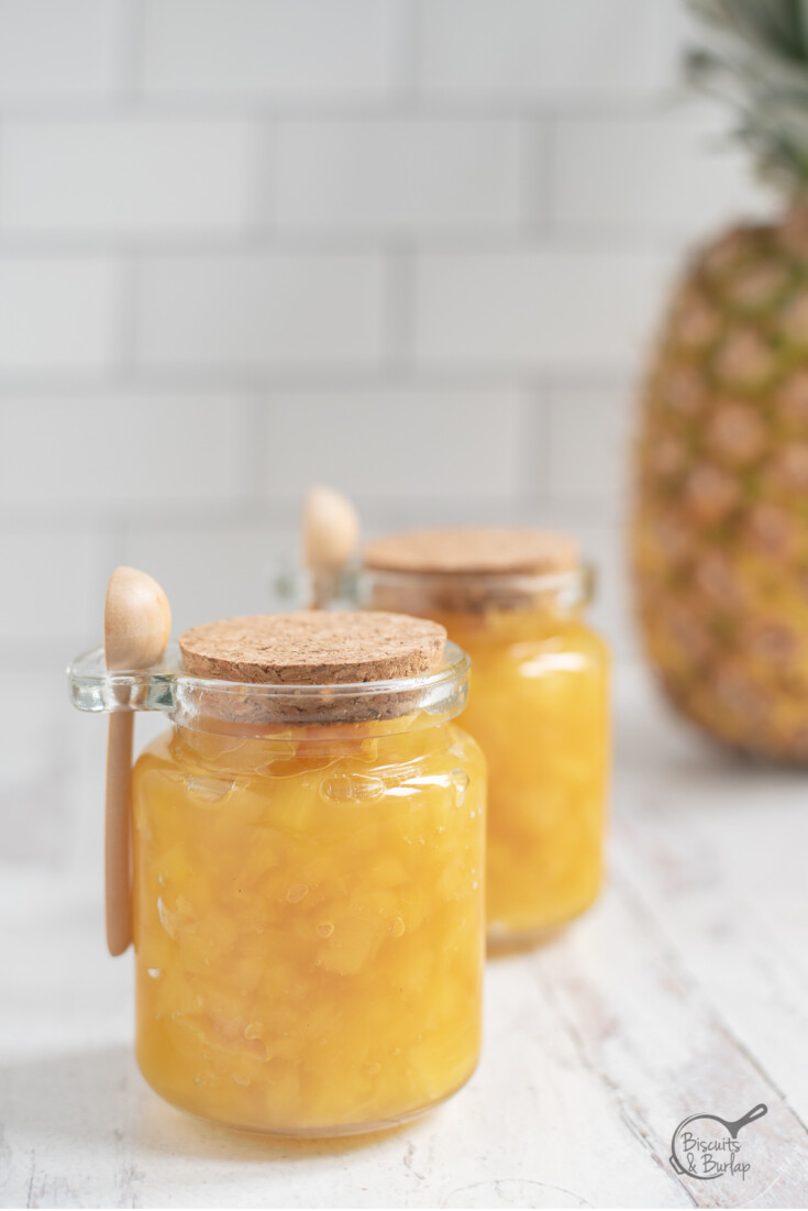 two jars of pineapple preserves in front of pineapple.