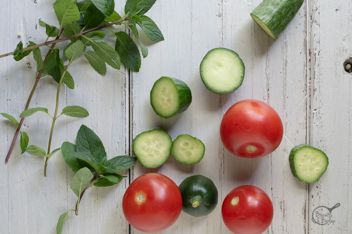 tomatoes, cocumbe slices, and mint leaves on a white background