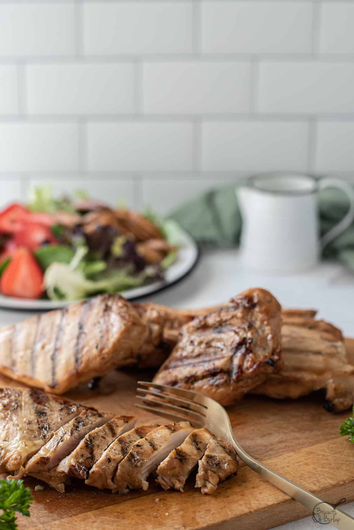 grilled chicken on board in front of salad