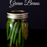 jar of quick pickled green beans on black background.